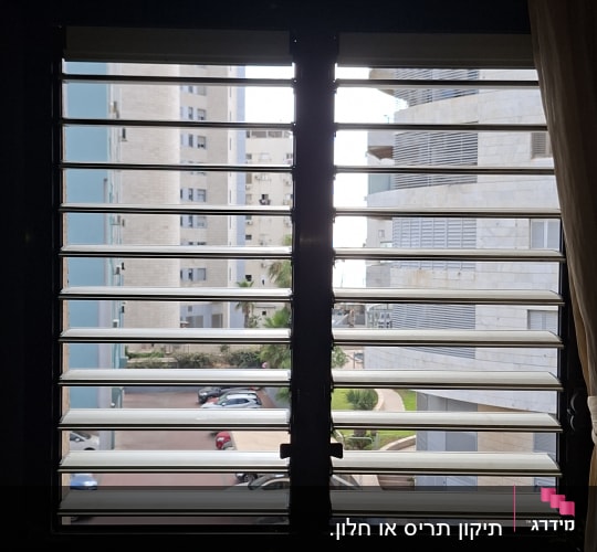 חלון עם תריסים נוף עירוני ברקע